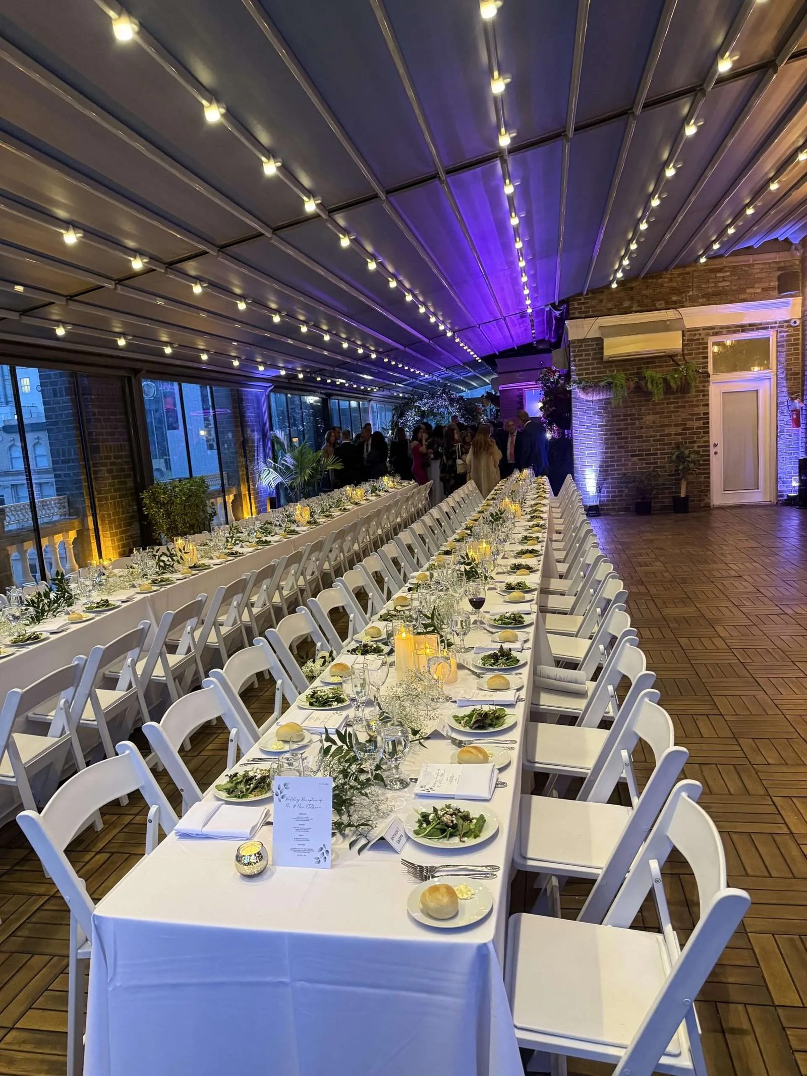 A wedding dinner on the enclosed Terrace beneath strings of lights