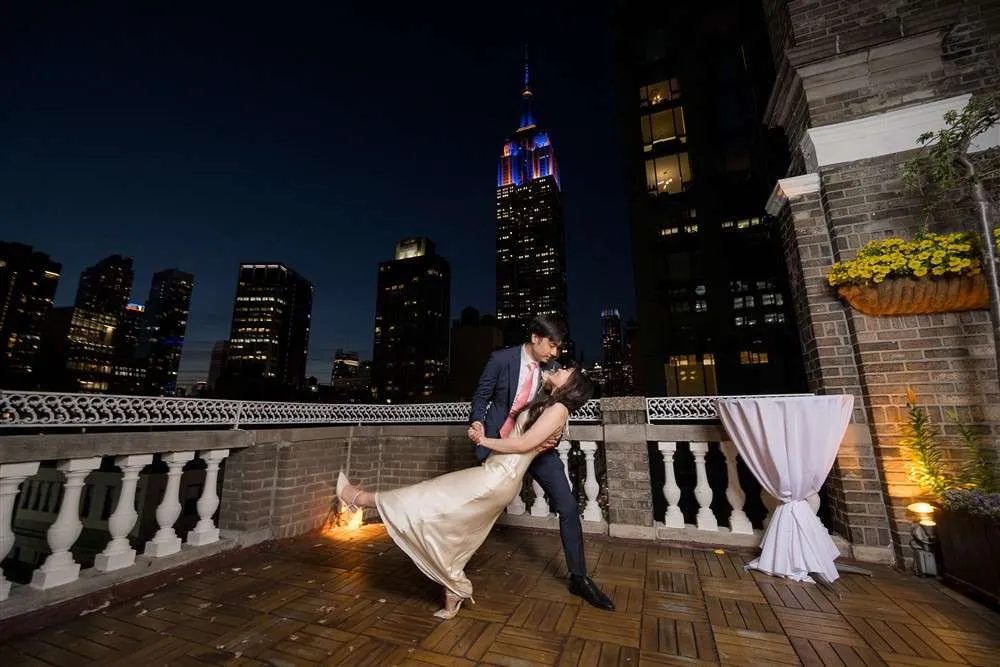 A couple's first dance on the Terrace at night, the Empire State Building behind them
